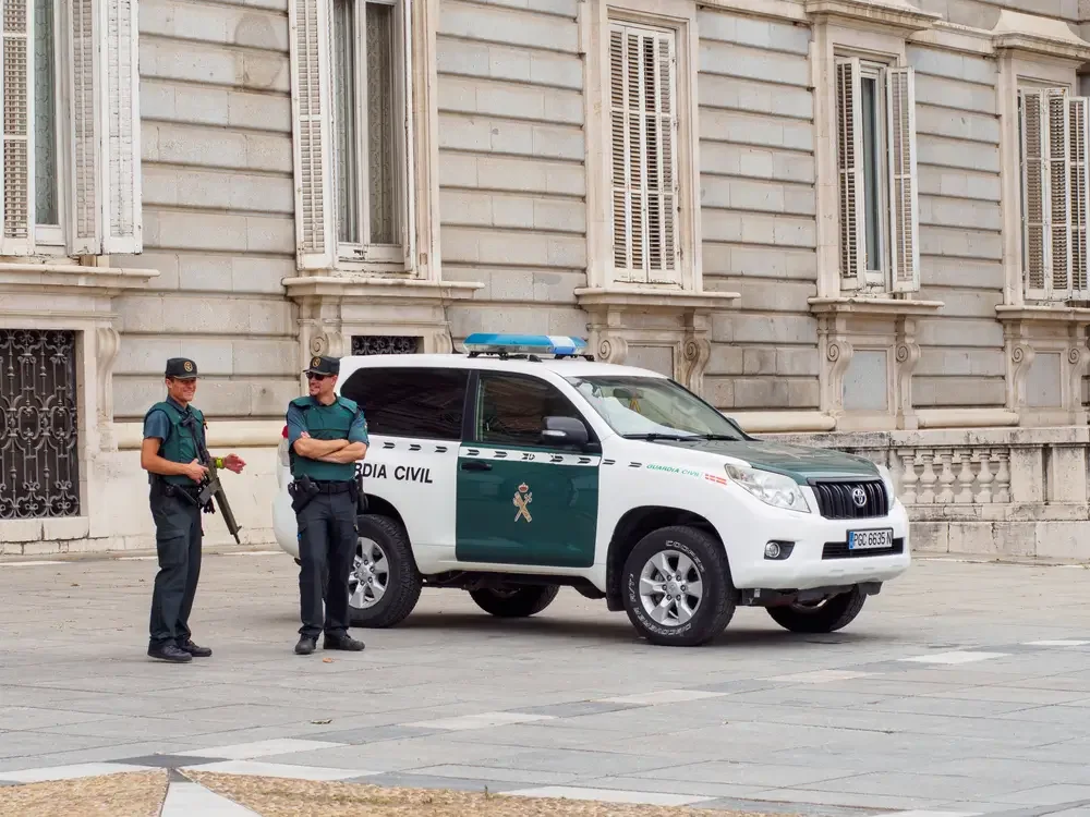 Dos guardias civiles conversan junto a su todoterreno de servicio frente al Palacio Real de Madrid