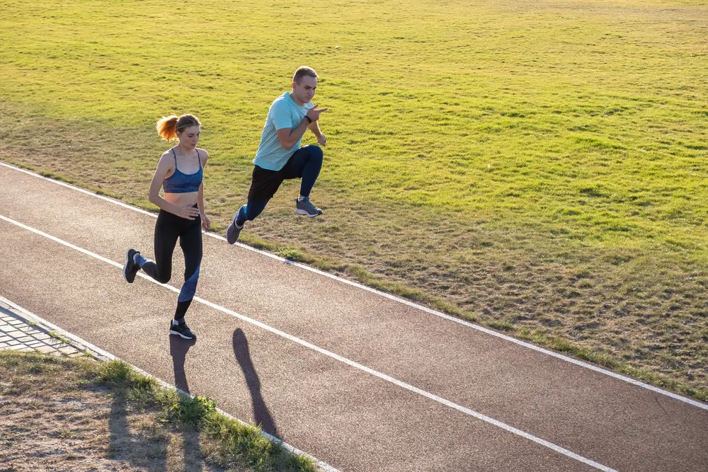 Aspirantes corriendo en una pista de atletismo exterior durante una prueba física de resistencia.