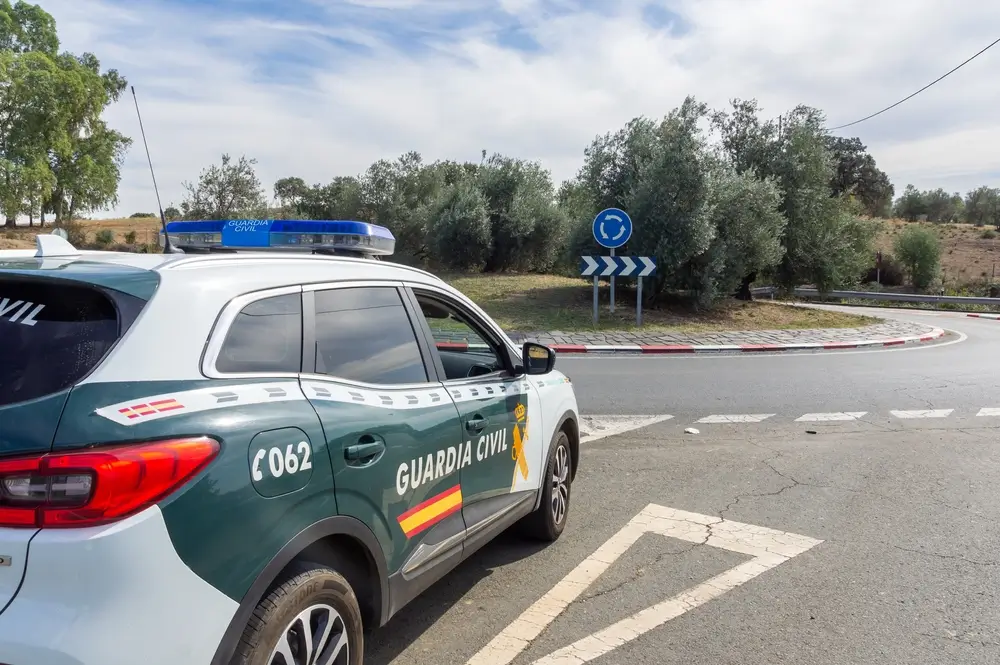 Coche patrulla de la Guardia Civil estacionado junto a una rotonda en una carretera durante un servicio de vigilancia.