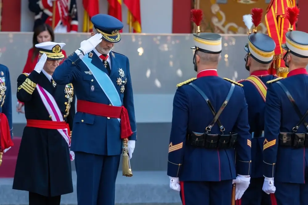 Ceremonia militar con el Rey Felipe VI saludando a cadetes uniformados ante la bandera de España en un acto oficial.