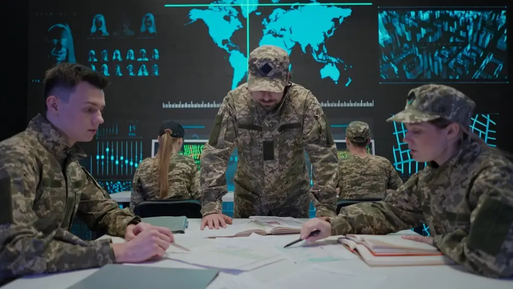 Oficial de mando impartiendo instrucciones a su equipo sobre mapas en una sala de operaciones con pantallas tácticas.