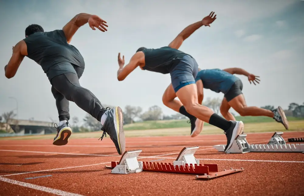 Corredores en la línea de salida de una pista de atletismo iniciando la prueba de resistencia para la Guardia Civil.
