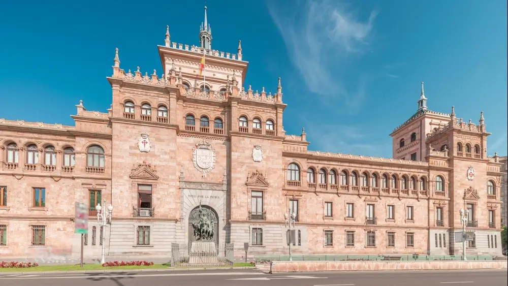 Edificio de la academia militar con fachada de piedra y arquitectura clásica bajo un cielo azul despejado.