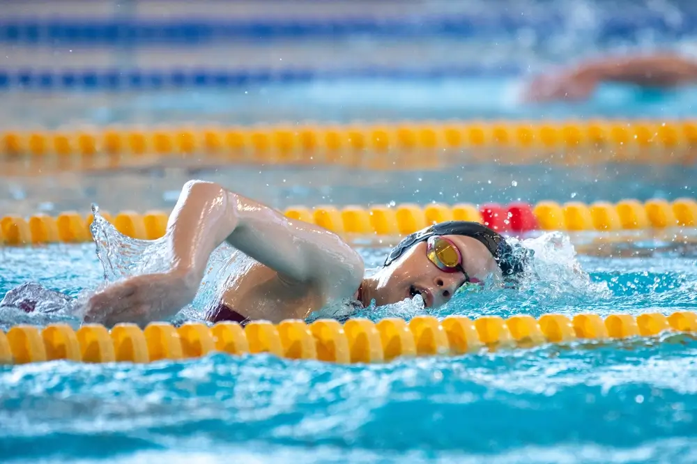 Nadadora realizando una serie de crol en una piscina durante un entrenamiento de natación para mejorar su soltura.