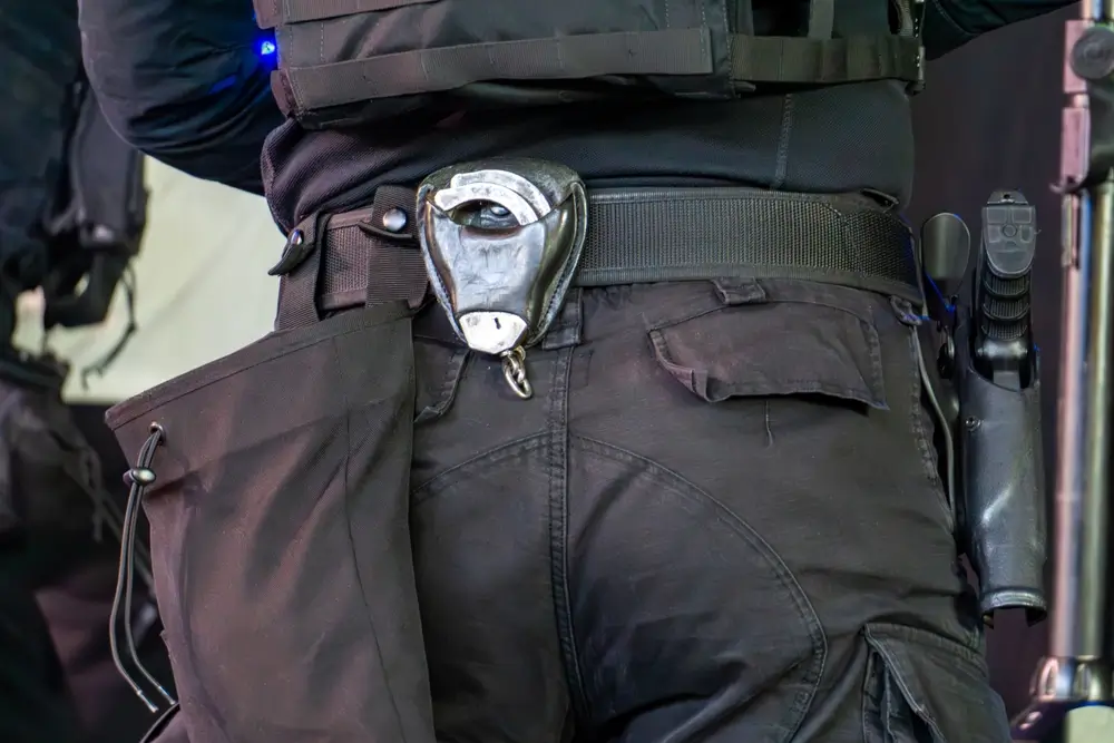 Primer plano del cinturón de servicio de un guardia civil con grilletes y el arma reglamentaria enfundada.