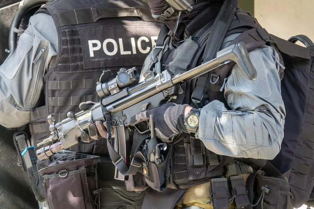 Agente de unidad especial con equipo táctico, chaleco de policía y arma automática lista para una intervención.