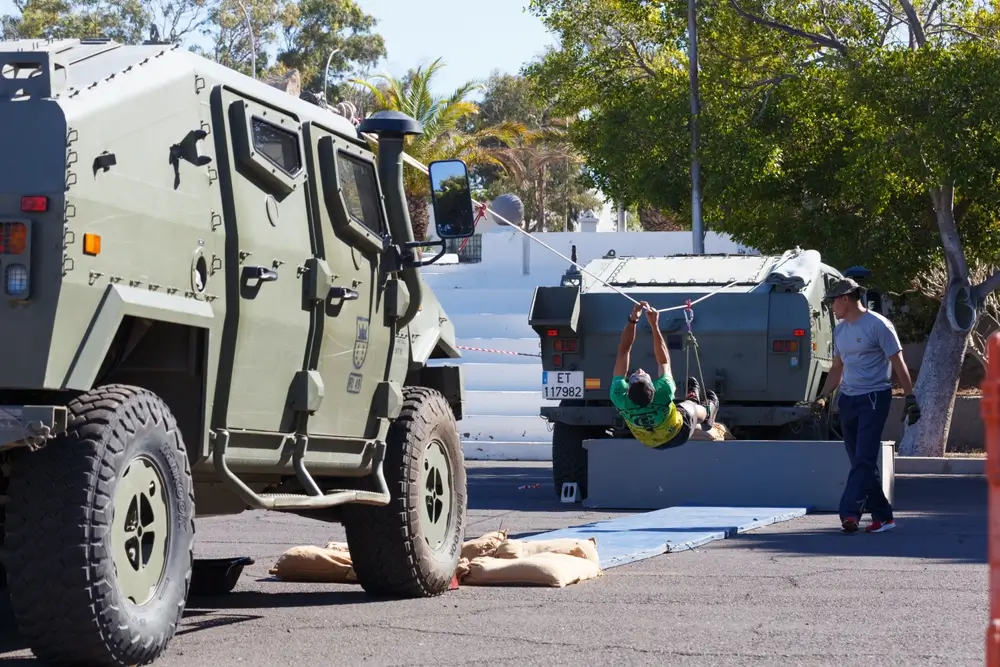Aspirante a guardia civil realiza pruebas físicas de paso de cuerda entre blindados en un entrenamiento militar.