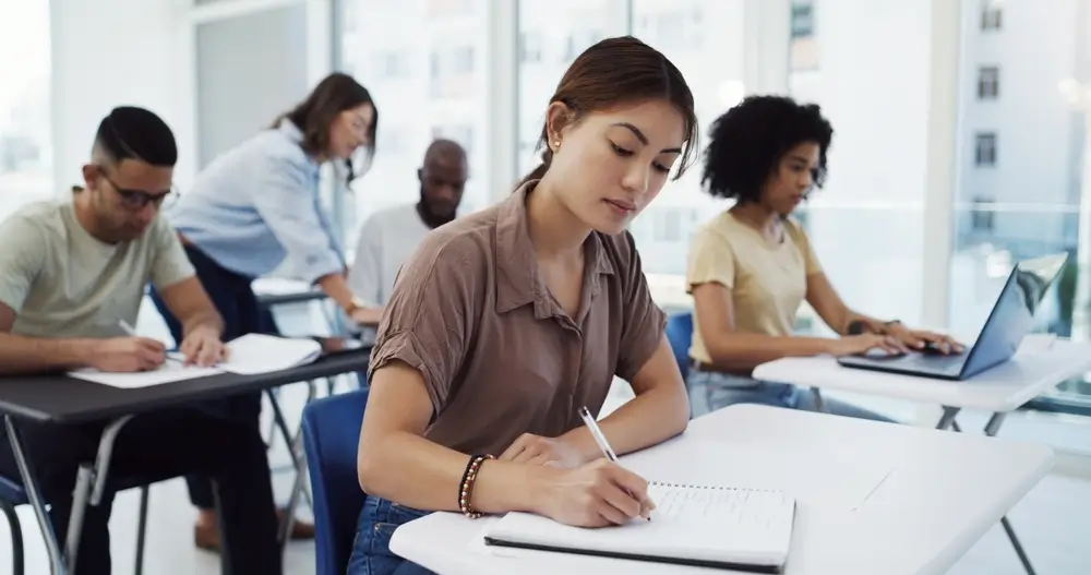 Opositores concentrados realizando exámenes y pruebas psicotécnicas en un aula de examen.