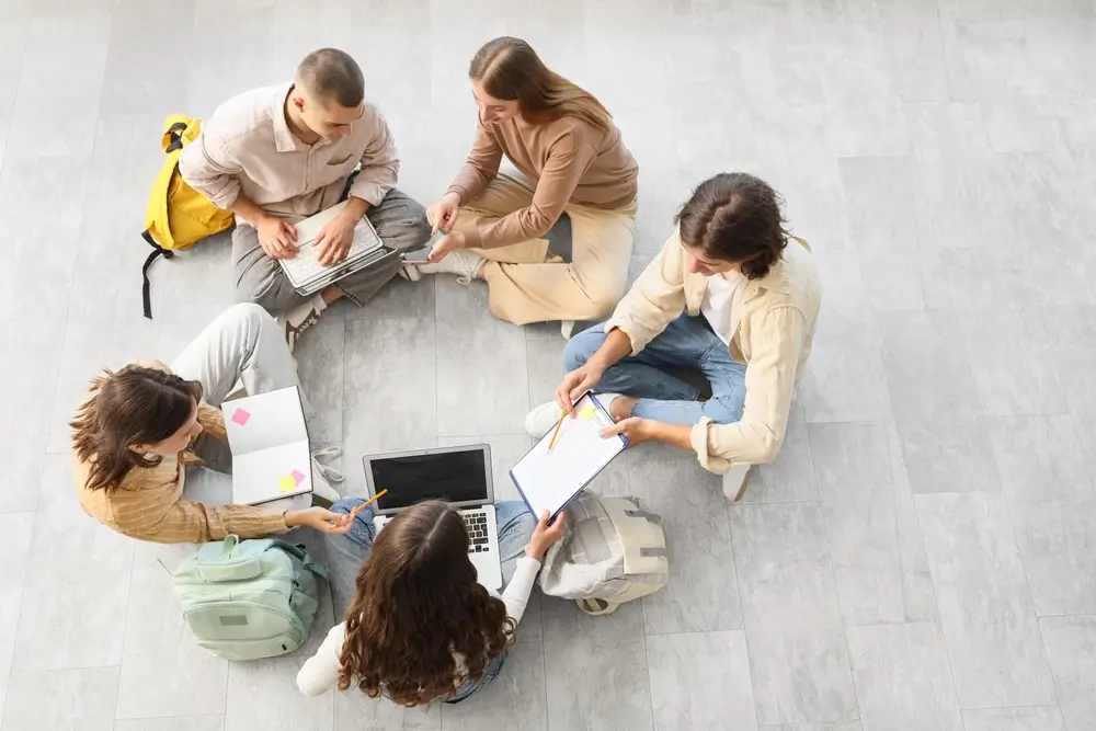 Grupo de aspirantes a policía estudiando juntos con portátiles y apuntes para preparar sus oposiciones.
