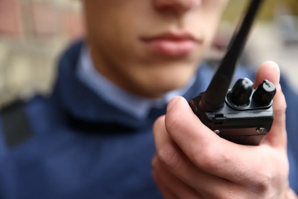 Agente de policía utilizando un walkie-talkie durante una intervención de seguridad y atención ciudadana.