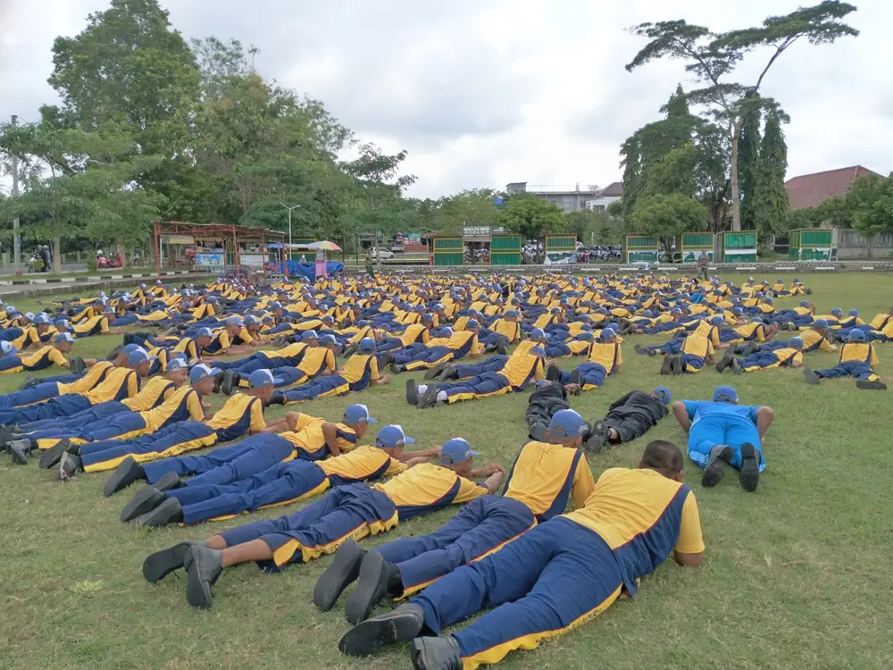 Aspirantes a la Guardia Civil realizando ejercicios de entrenamiento físico sobre el césped con uniforme deportivo.