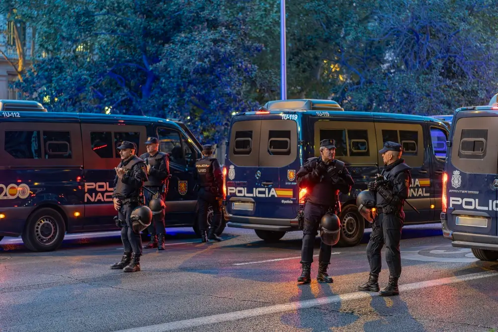 Agentes de la Policía Nacional y la Guardia Civil patrullando una calle mojada en un operativo de seguridad ciudadana.