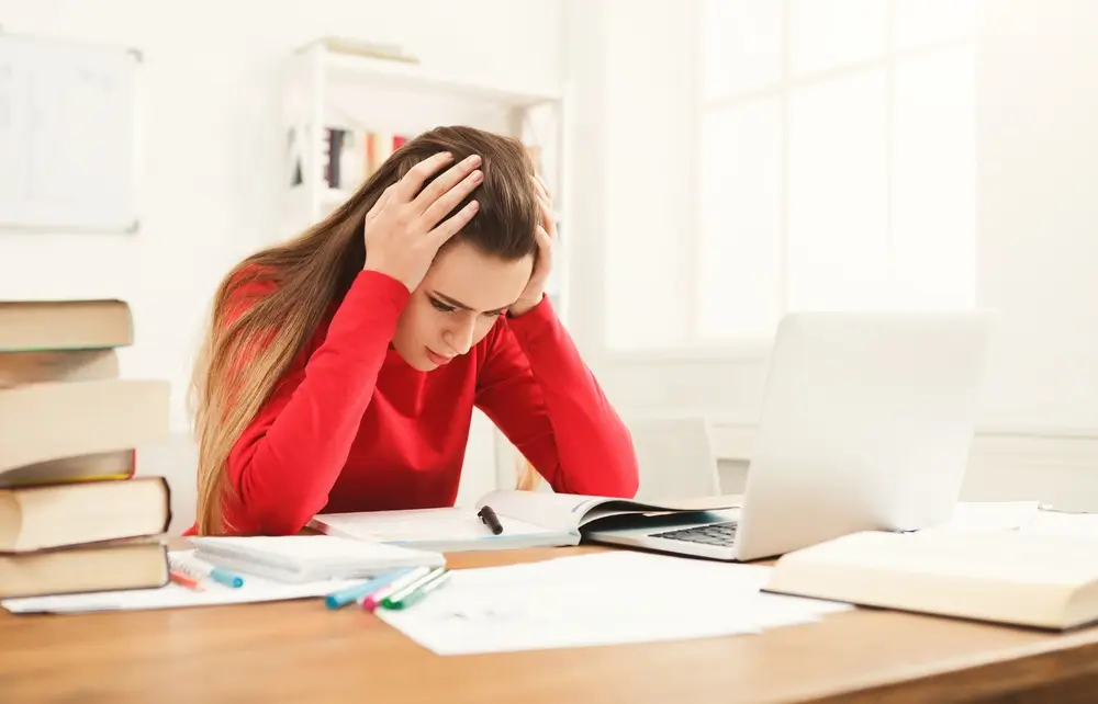 Opositora concentrada estudiando en su escritorio con libros y portátil para los psicotécnicos de la Guardia Civil.