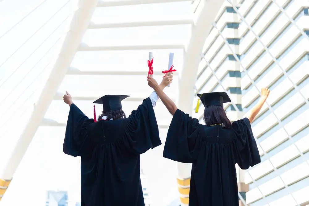 Graduados universitarios de espaldas alzando su título académico como parte de sus méritos académicos.