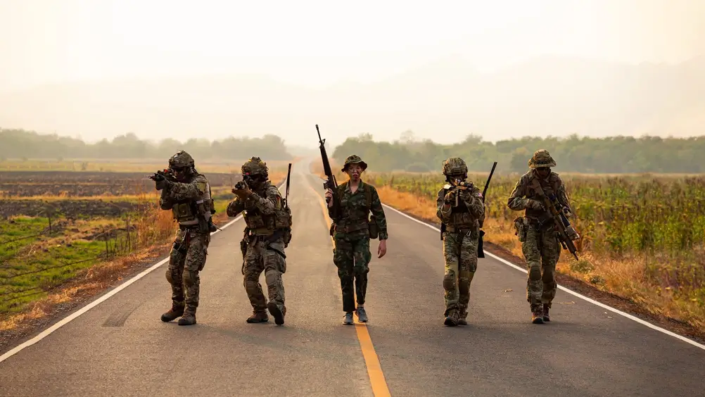 Militares profesionales patrullando una carretera con equipo táctico completo en una misión de vigilancia.