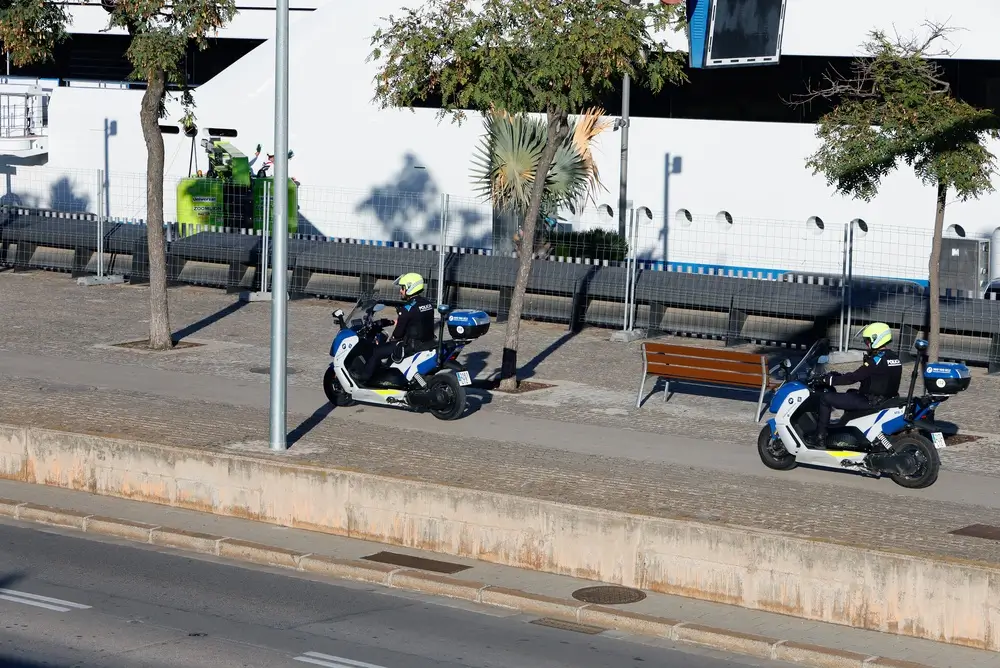 Dos agentes de policía motorista con equipo completo y casco patrullando en motocicletas oficiales por la ciudad.