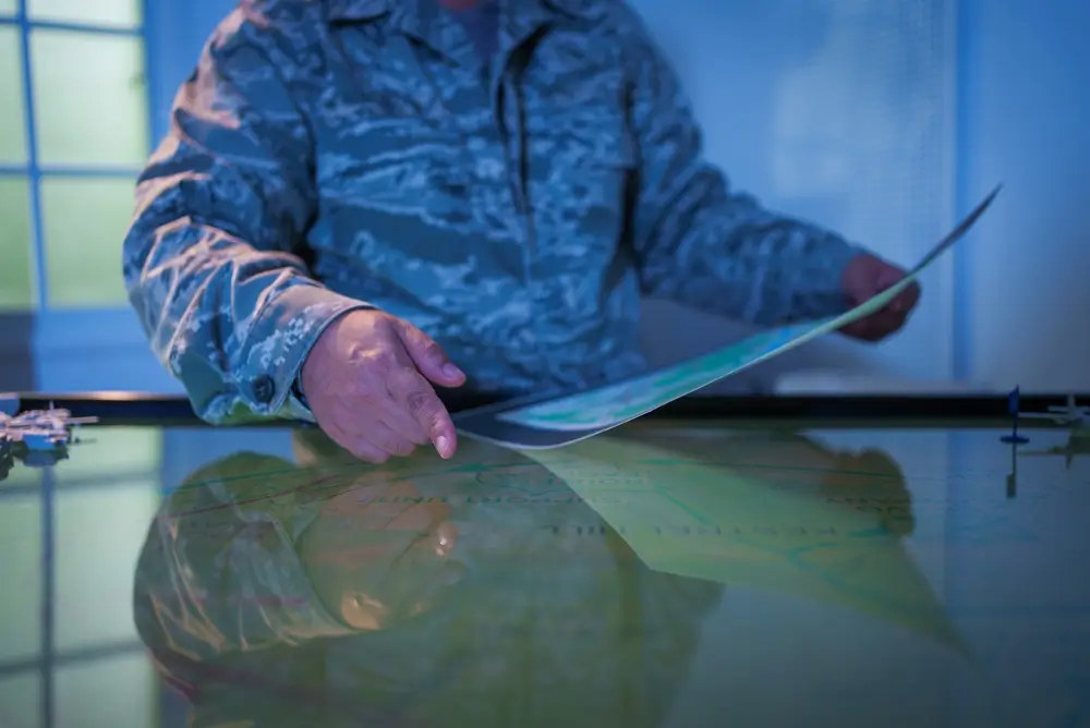 Oficial de la Guardia Civil con uniforme entrega documentación oficial sobre una mesa durante el proceso de selección.