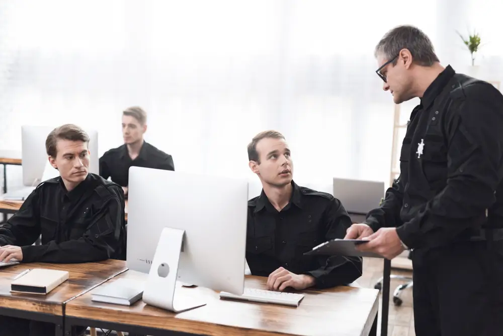 Aspirantes a Guardia Civil en un aula de formación realizando pruebas psicotécnicas en ordenadores con un instructor.